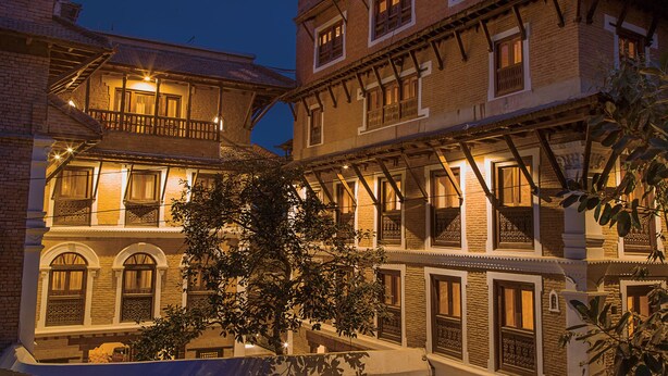 Un edificio tradicional con varios balcones y ventanas, que presenta fachada de ladrillo y barandillas de madera.