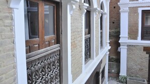 Un estrecho callejón entre edificios con ventanas en arco y detalles blancos.