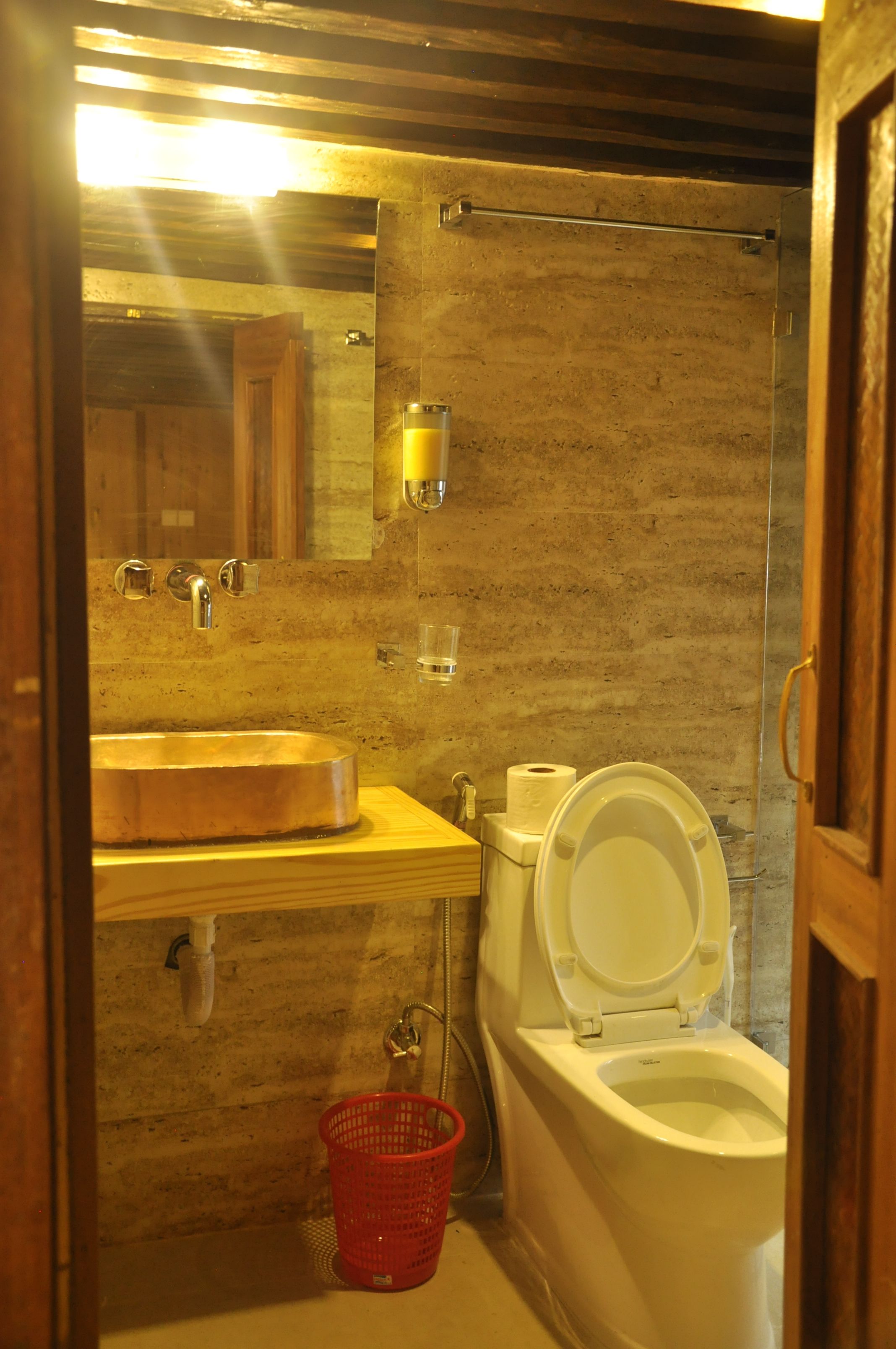 A bathroom with a wooden vanity, a sink, a toilet, and a red basket.