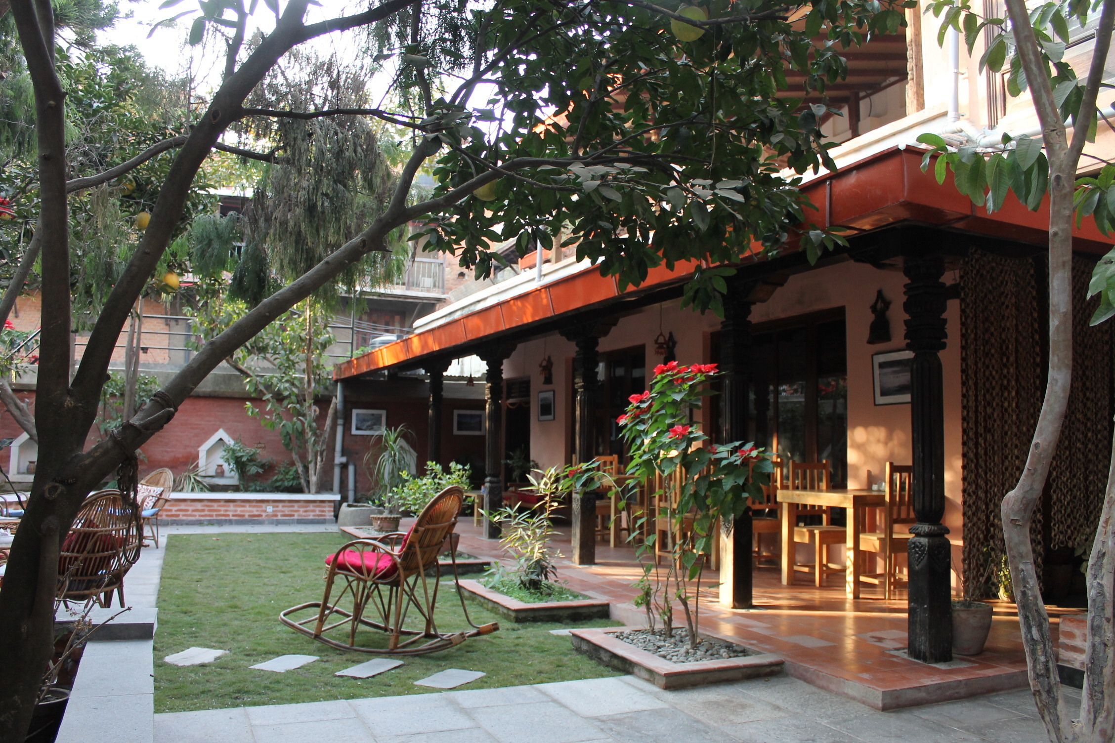 A courtyard with a lawn, potted plants, and outdoor furniture.