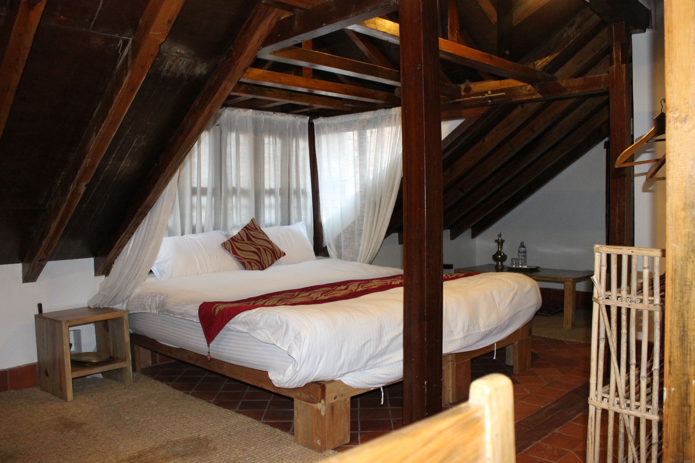 A bedroom with a wooden bed, a nightstand, and a window with curtains.
