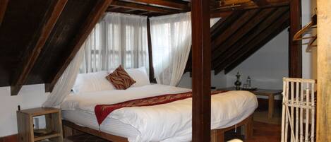 A bedroom with a wooden bed, a nightstand, and a window with curtains.