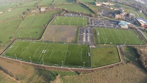 An aerial view of a sports complex with multiple football fields, parking areas, and residential buildings. - The Quigley Residence (Garraun)