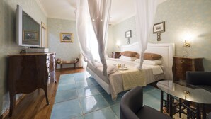 Une chambre à coucher avec un lit à baldaquin, une table de chevet, une chaise, un téléviseur et un petit meuble.