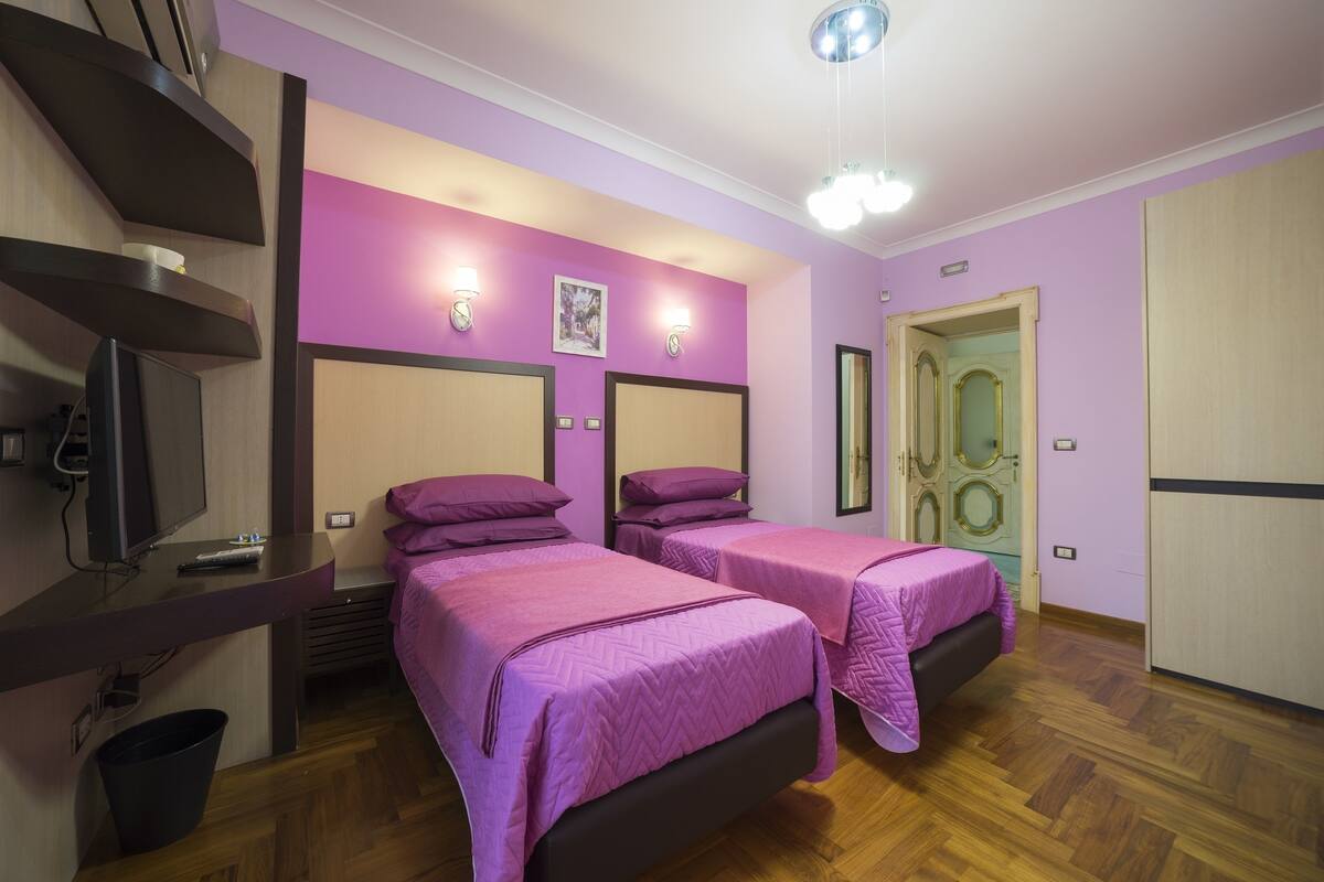 A room with two beds, a TV, and a door with a decorative handle.