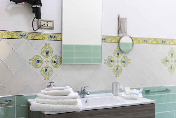 Un baño con lavamanos, espejo y una pila de toallas.