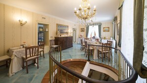 Un espace repas agrémenté d’un lustre, de chaises en bois, d’une table à manger et d’un escalier.