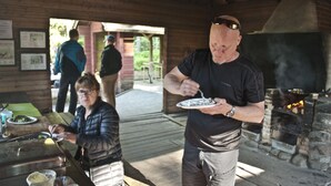Un espace de restauration extérieur de style rustique, doté d’un four en briques, de tables en bois et d’une allée couverte.