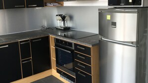Une cuisine moderne avec des meubles de couleur noire, un réfrigérateur en acier inoxydable, un four à micro-ondes et un four encastré.