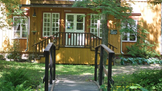 Un bâtiment en bois doté d’une terrasse en bois et d’une enseigne indiquant : « Réception Vastaantottoto ».