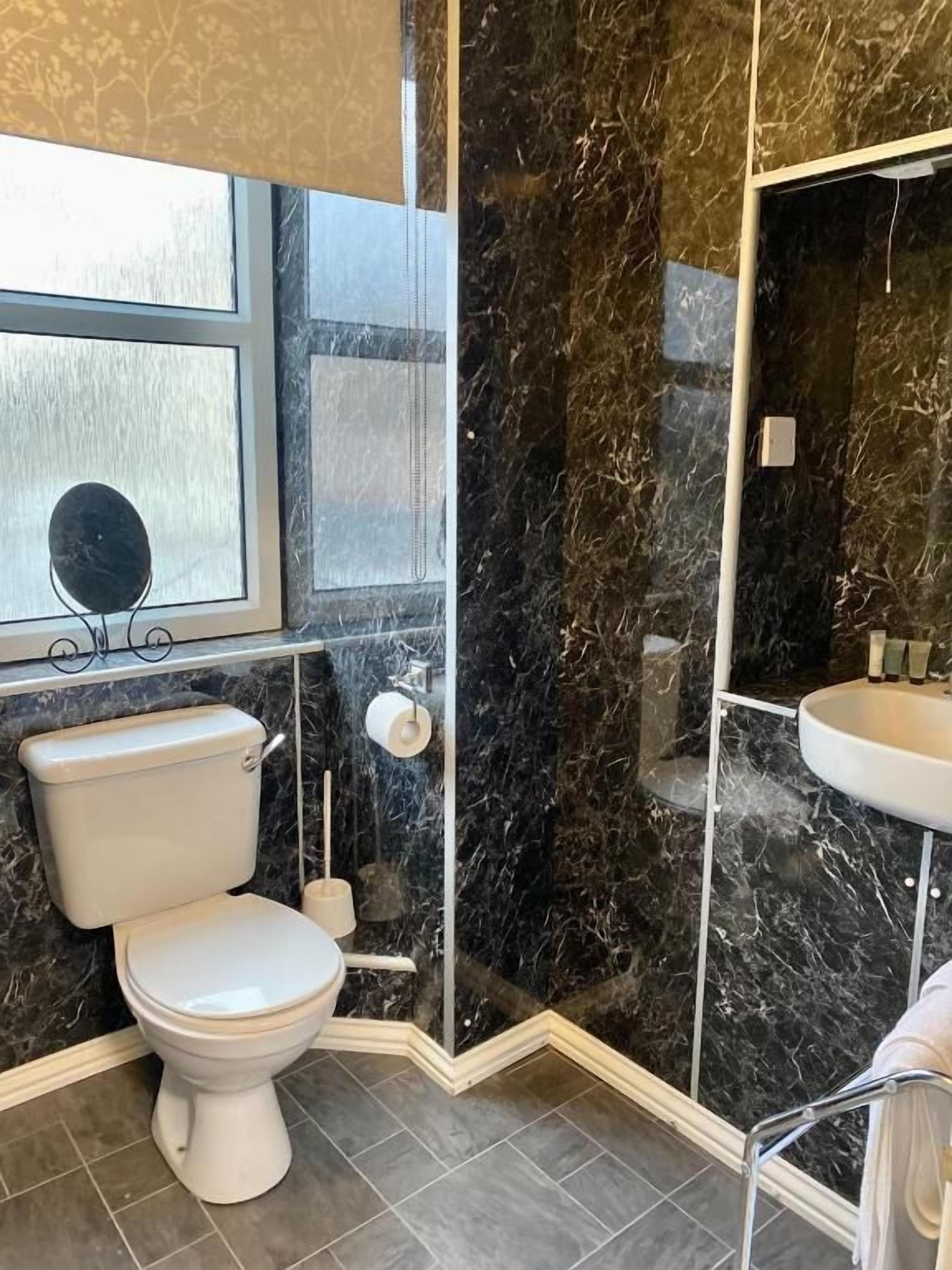 A bathroom with a toilet, sink, and a glass-enclosed shower area.