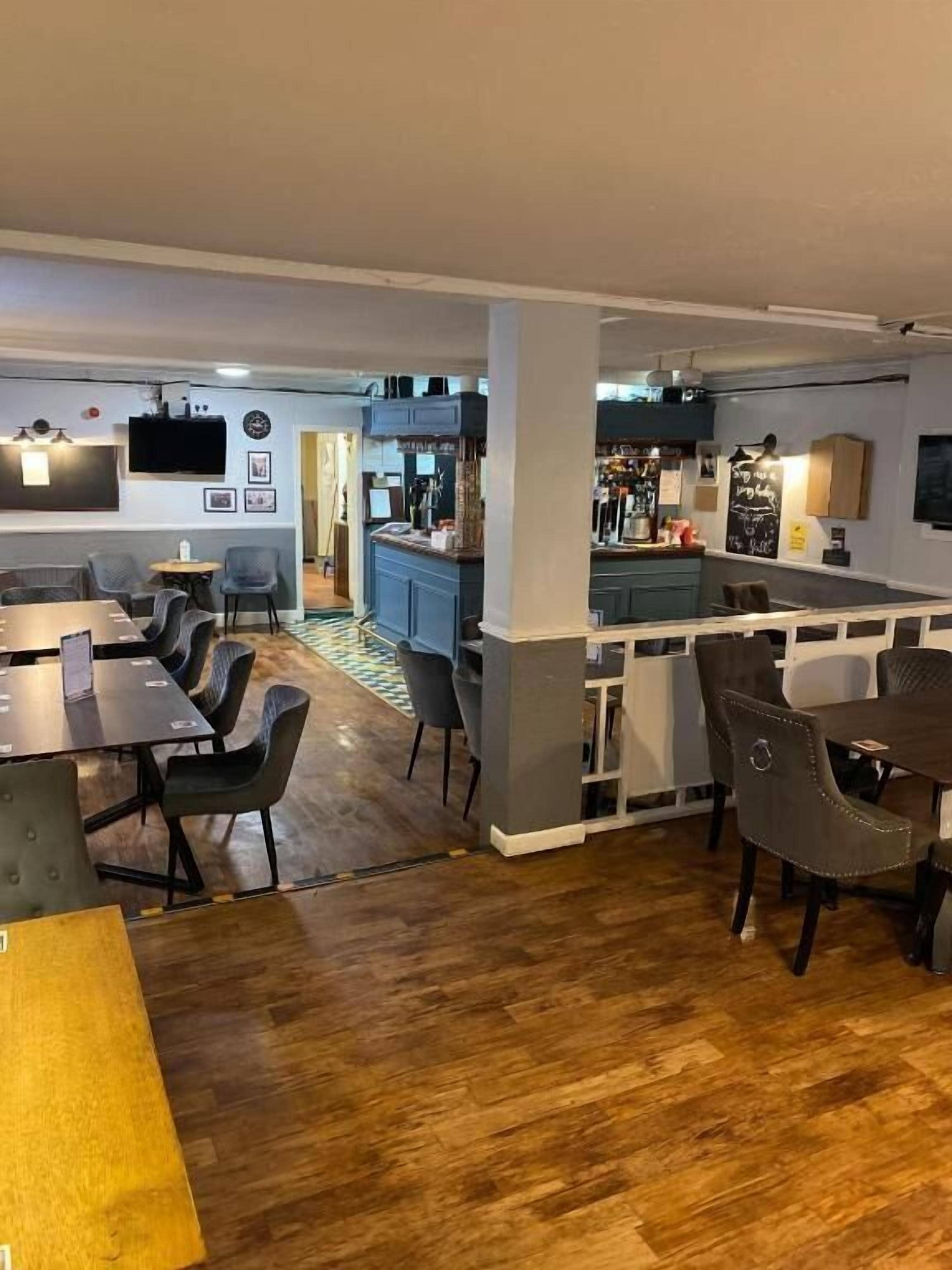 A modern interior with a bar area, seating arrangements, and a kitchen in the background.