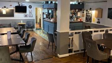 A modern interior with a bar area, seating arrangements, and a kitchen in the background.