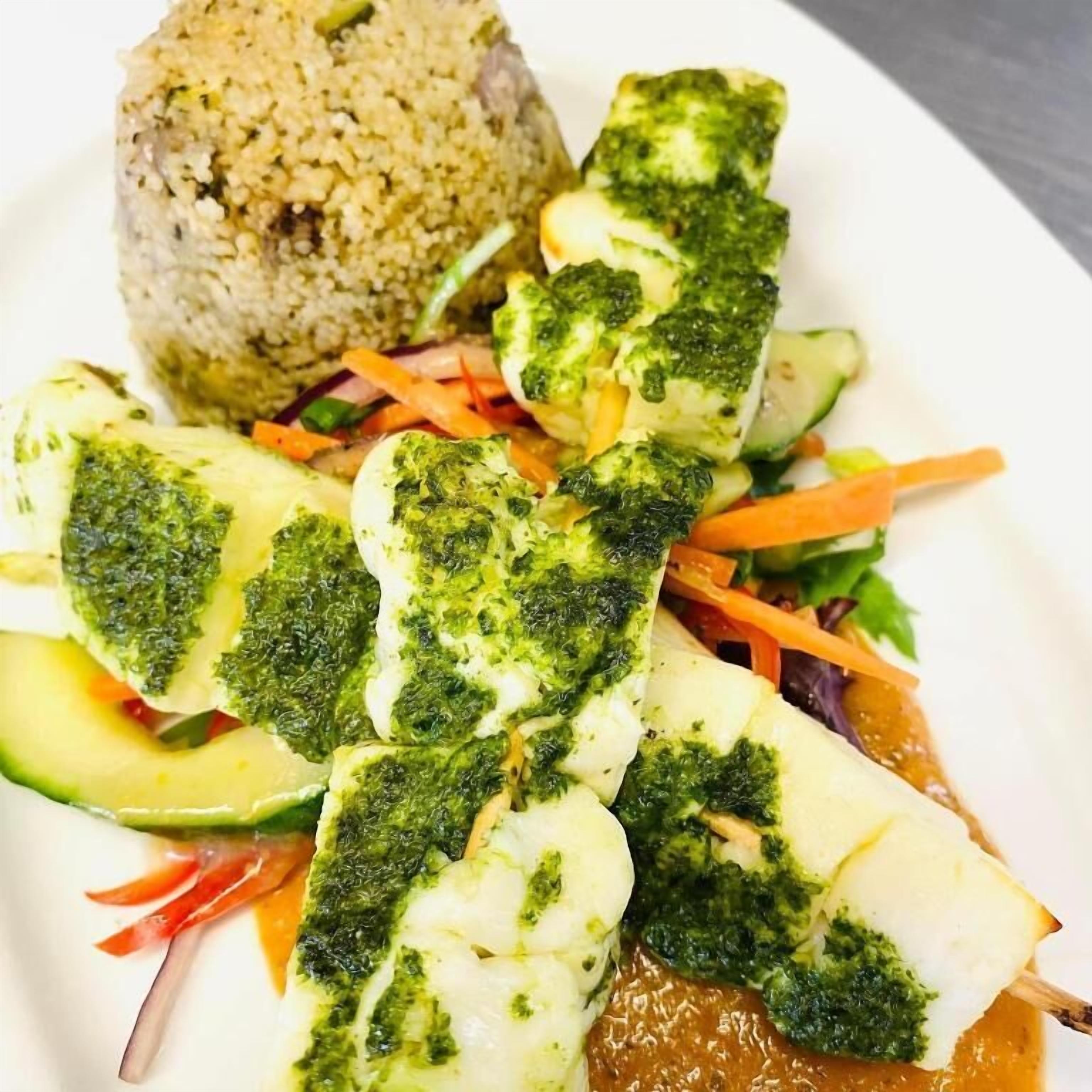 A plate with fish fillets, a rice ball, and a vegetable medley.