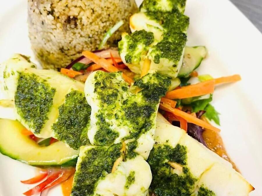 A plate with fish fillets, a rice ball, and a vegetable medley.
