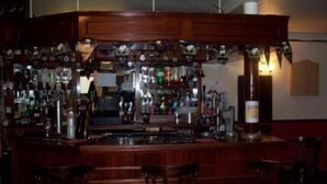 A bar area with wooden bar counters and stools.