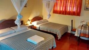 Una habitación con dos camas, cada una con dosel, una mesa con sillas y una lámpara colgante.