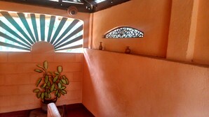 Una habitación con una planta en maceta, un adorno de pared y una ventana con ventilador.