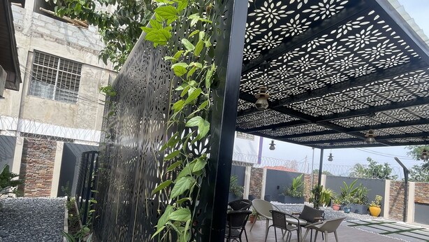 Zona de pati amb una pèrgola, seients i plantes.