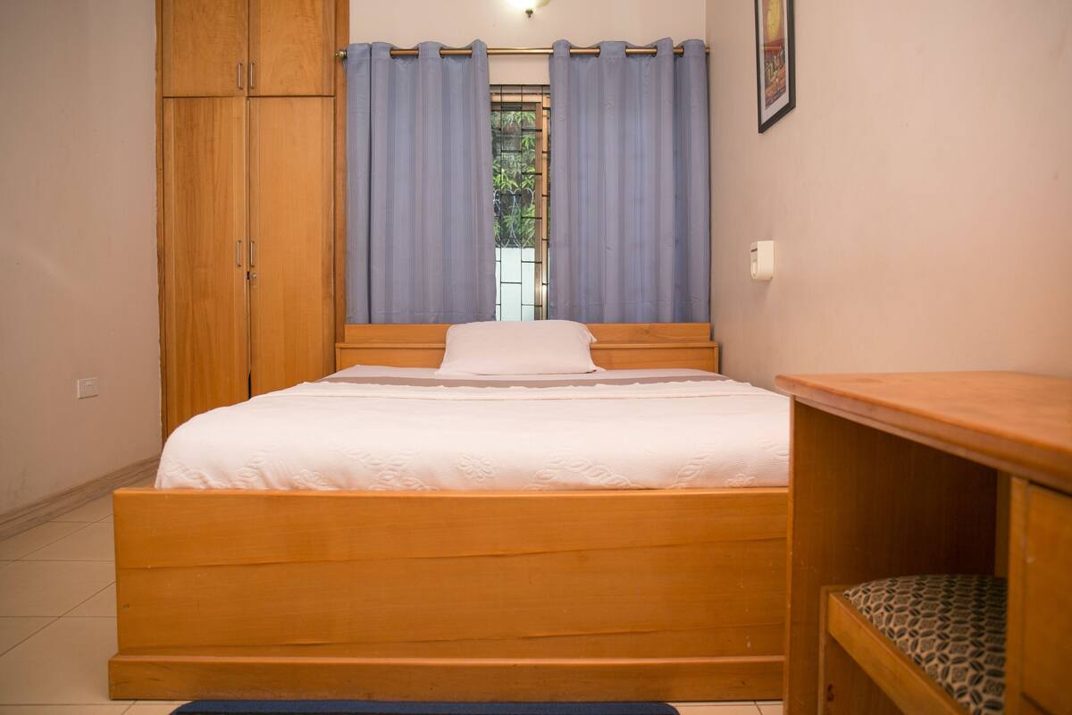 A bedroom with a wooden bed, a nightstand, and a wardrobe.