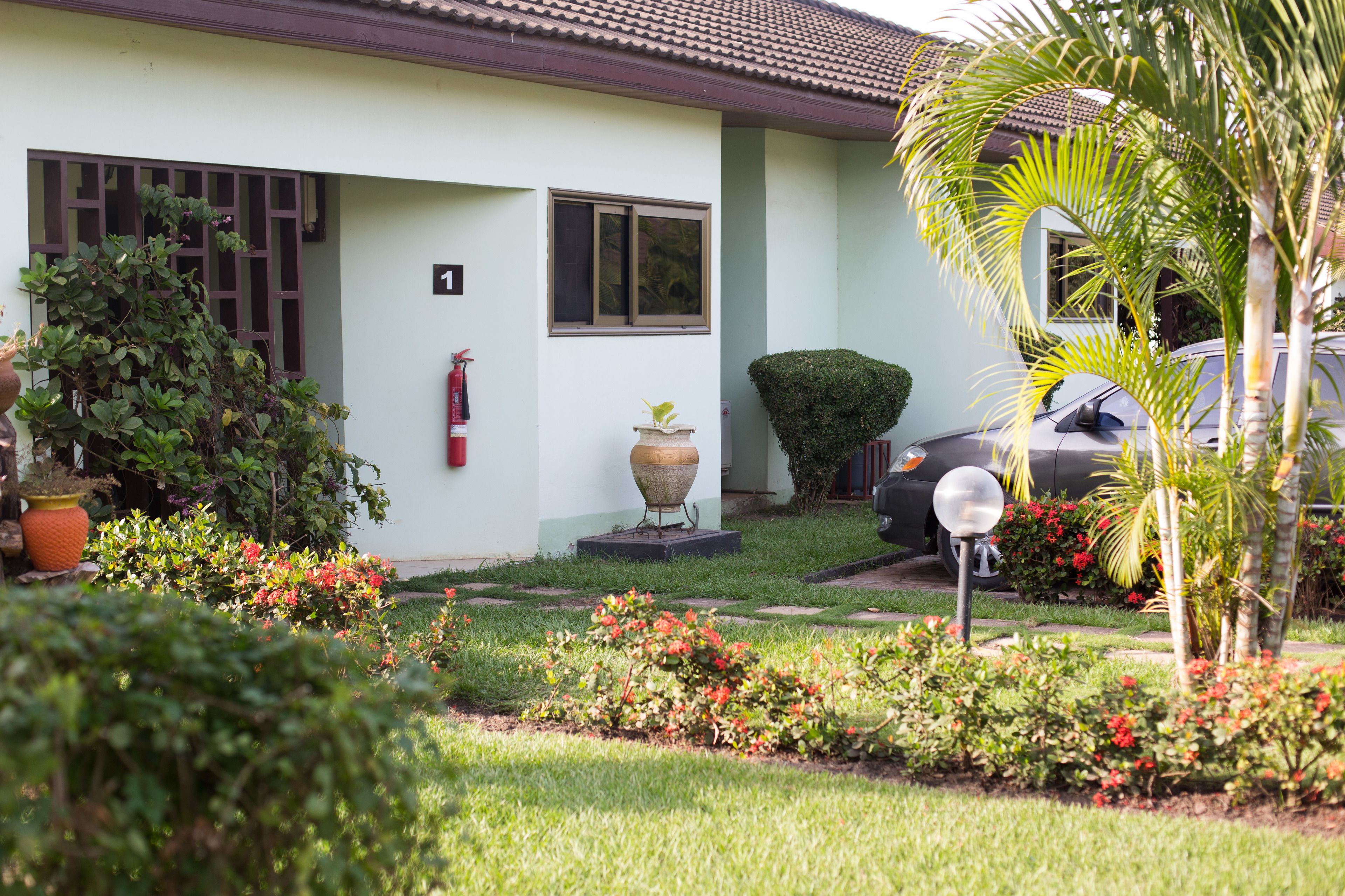 A house with a well-maintained garden, a fire extinguisher, and a car parked in the driveway.