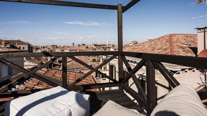 A rooftop terrace with a wooden railing, offering a view of a cityscape with terracotta rooftops and a clear blue sky. - MYSWEETPLACE - San Marco Apartments (Venice)