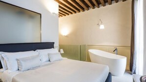 A bedroom with a large bed, a built-in bathtub, and a wall-mounted light fixture. - MYSWEETPLACE - San Marco Apartments (Venice)