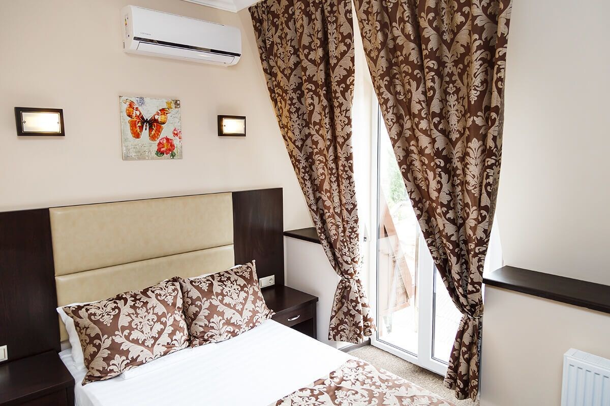 Une chambre à coucher comprenant un lit, des tables de chevet, une tête de lit, un climatiseur et des rideaux.