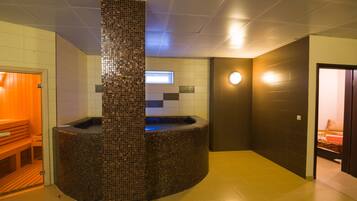 Relax in a serene spa area with a circular hot tub, wooden bench, and digital display.