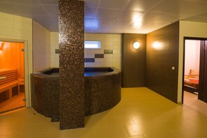 Un espace de détente avec un jacuzzi orné de mosaïques, des bancs en bois et une petite fenêtre.