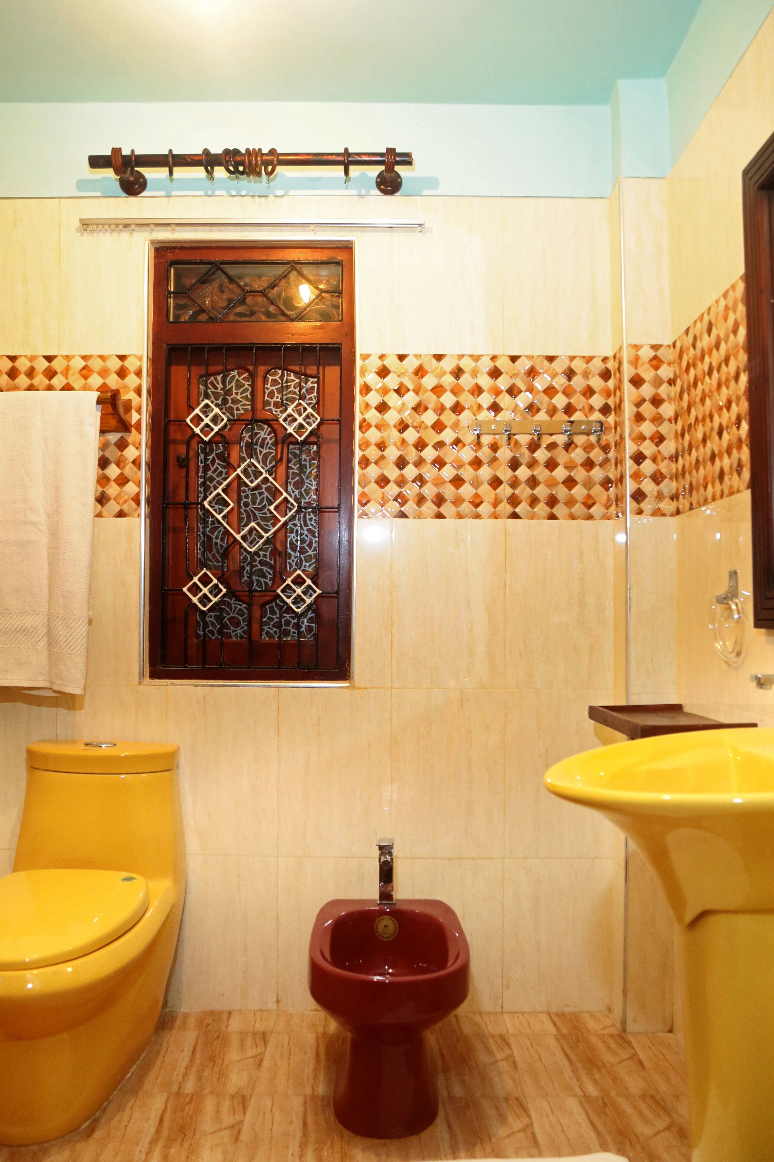 A bathroom with a yellow toilet, a red bidet, and a yellow sink.