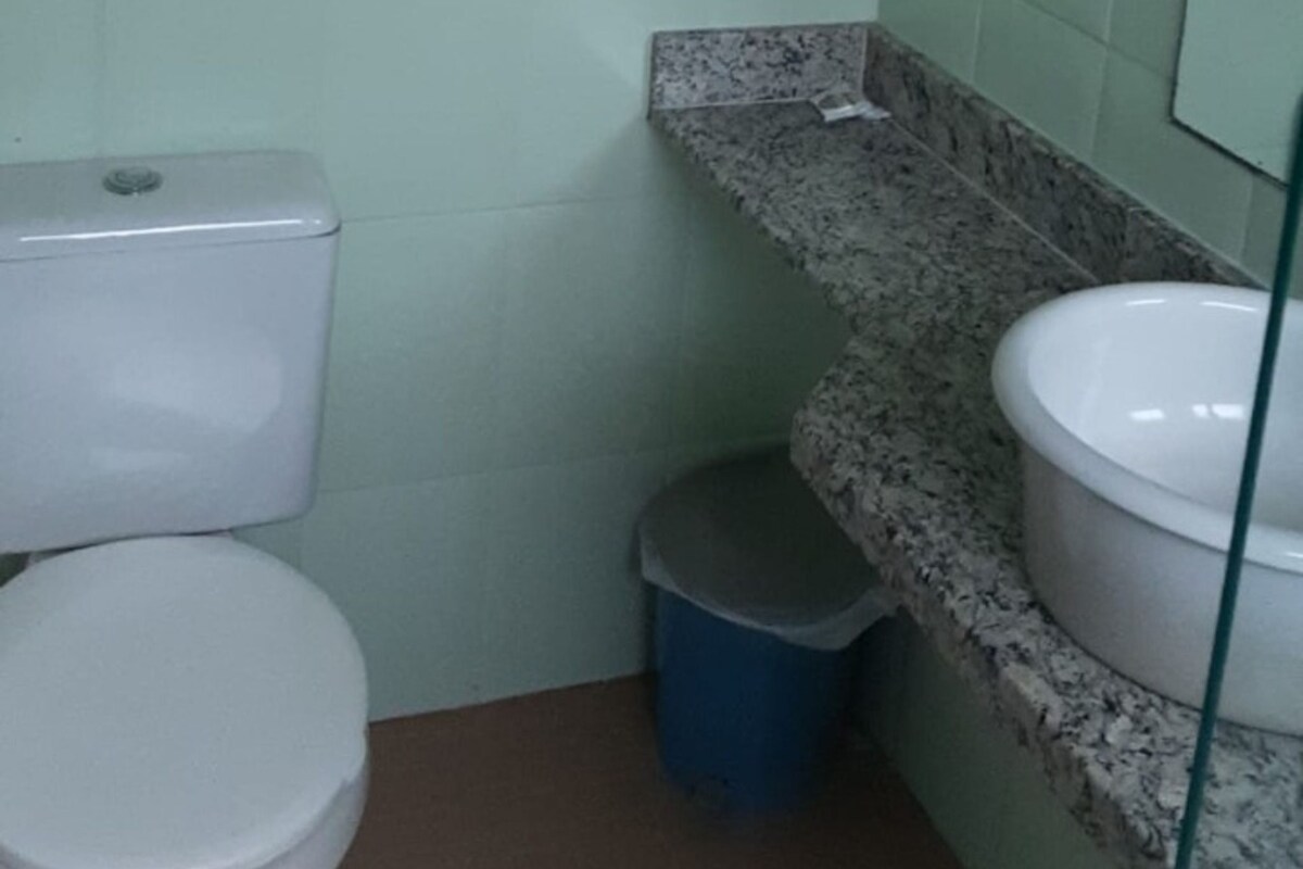 Un baño pequeño con inodoro, lavamanos y un cubo de basura.