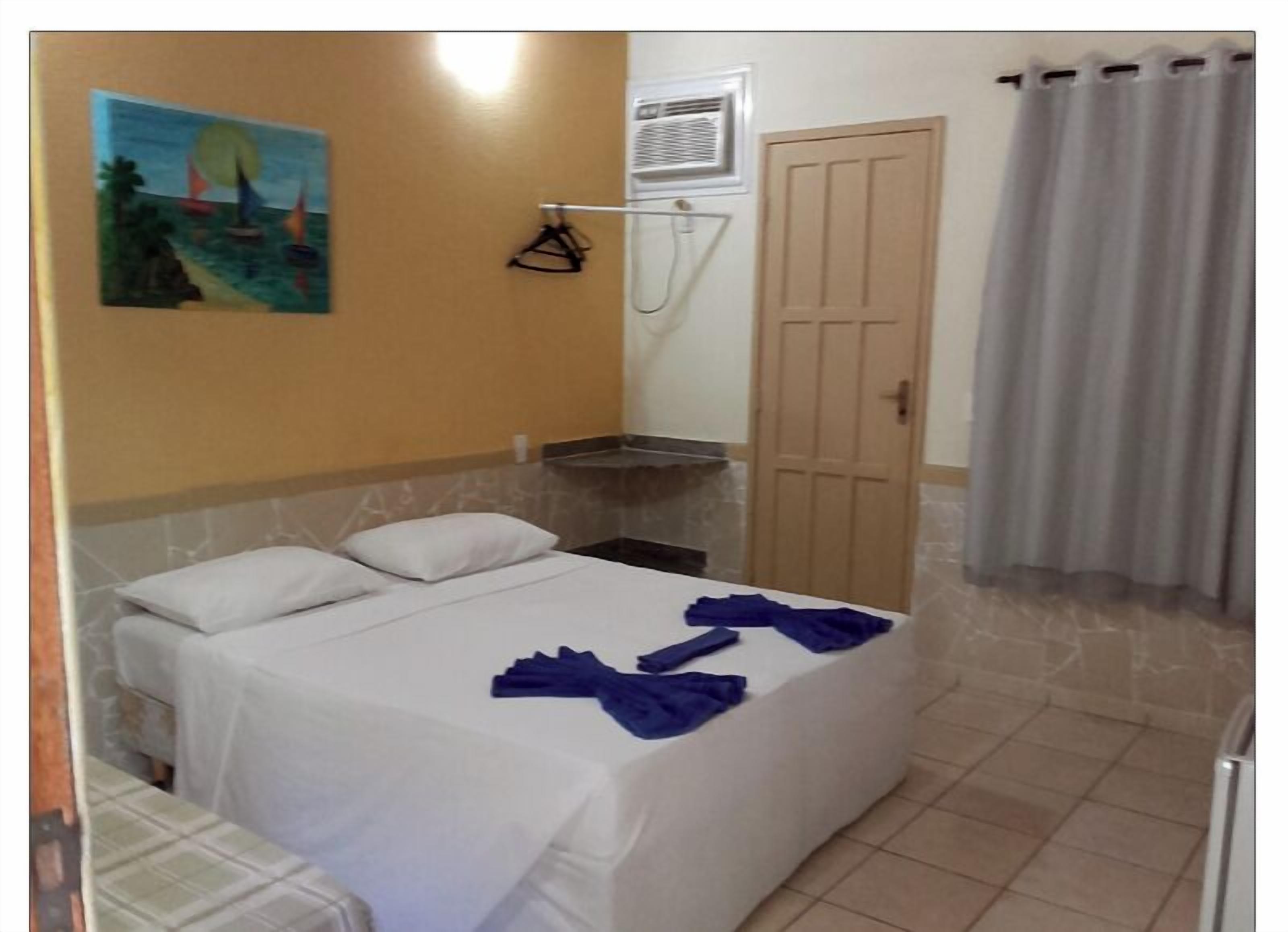 Habitación de hotel con cama, un cuadro en la pared, zona de ducha y una puerta.