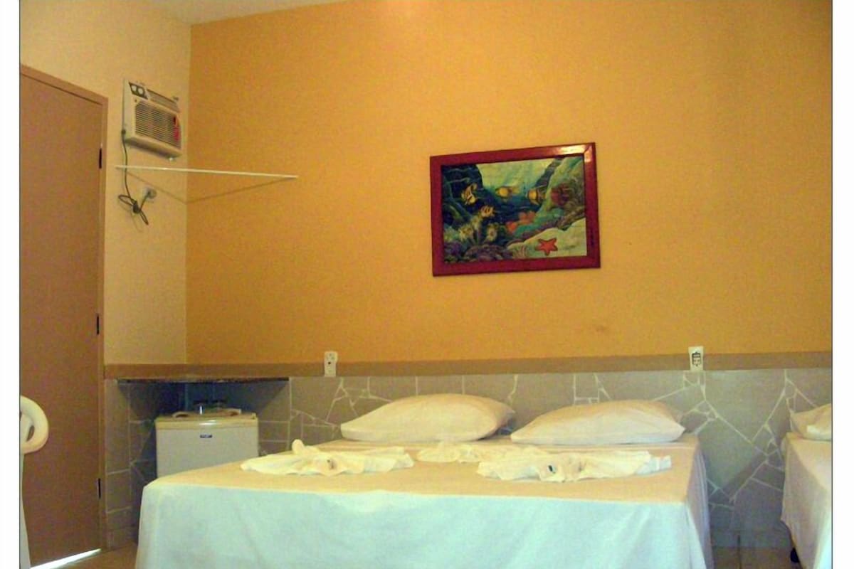 Una habitación de hotel con cama, una mesita, un calentador de pared y un cuadro.