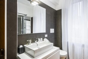 A modern bathroom with a large mirror, white sink, and a toilet. - MYSWEETPLACE - Rialto Apartments (Venice)