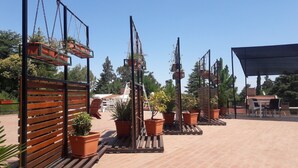 An outdoor patio area with wooden benches, potted plants, and a covered seating area. - Complejo Rumipal (Villa Rumipal)