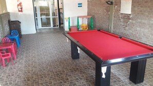 A pool table in a room with tiled flooring, a fire extinguisher, and a door with glass panels. - Complejo Rumipal (Villa Rumipal)