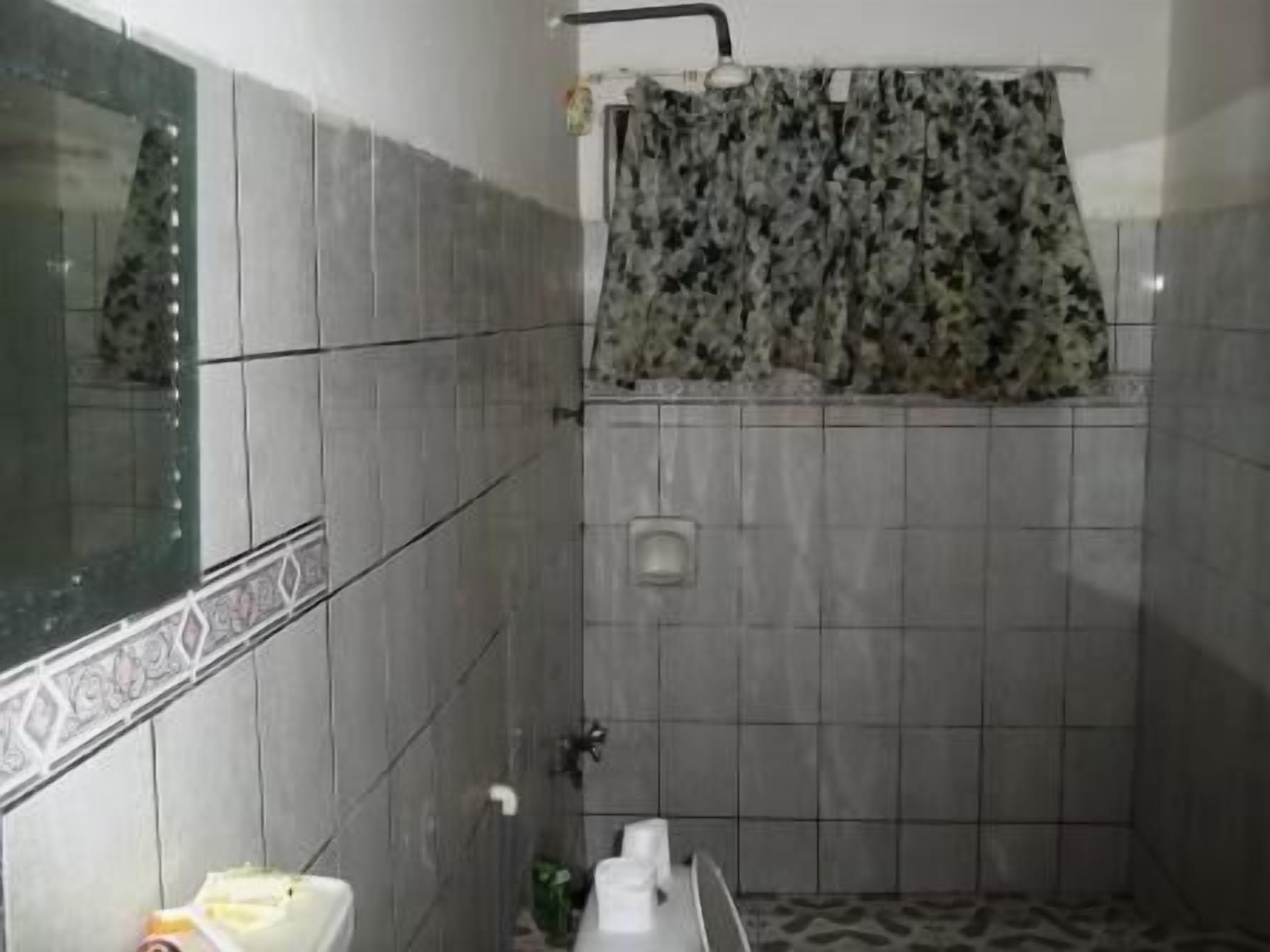 A small bathroom with a toilet, sink, and shower area.