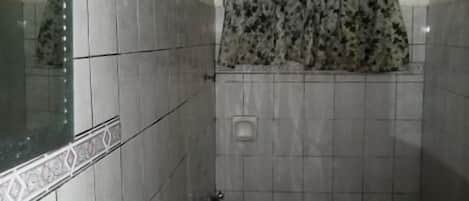 A small bathroom with a toilet, sink, and shower area.