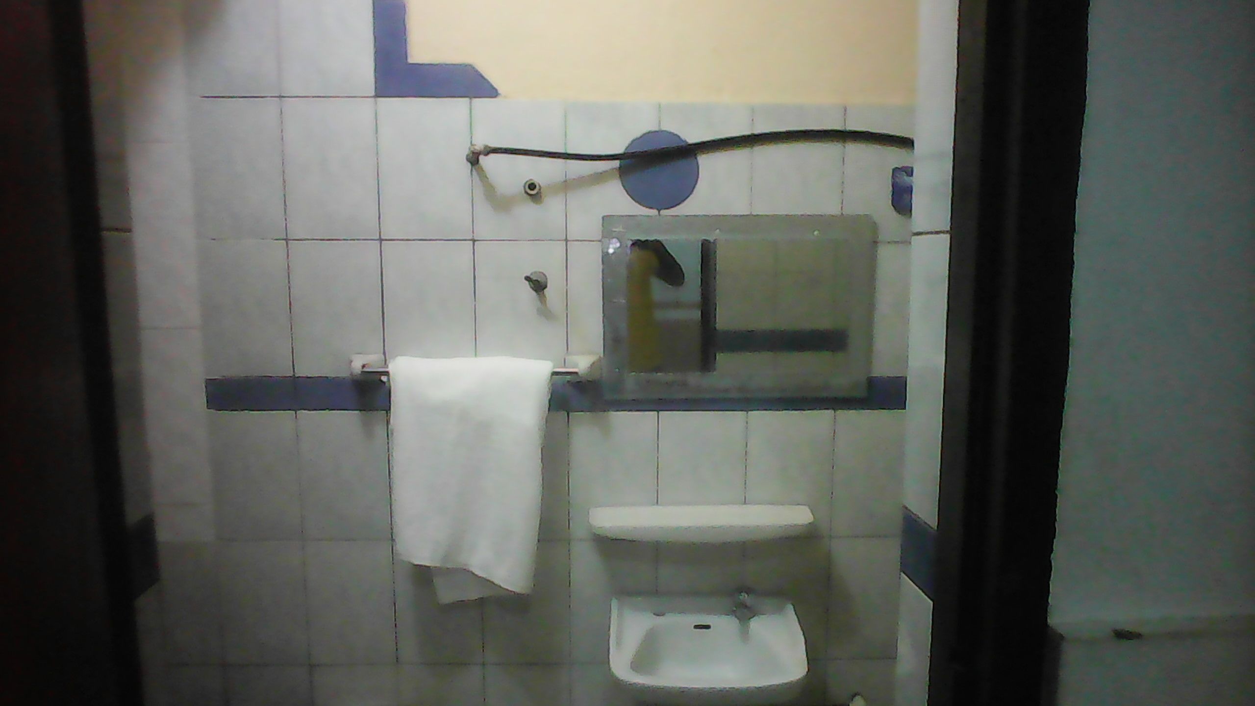 A small bathroom with a white sink, a mirror, and a towel hanging on the wall.