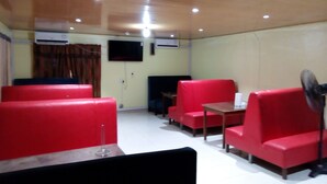 Una habitación con asientos rojos, un televisor montado en la pared y un equipo de aire acondicionado.