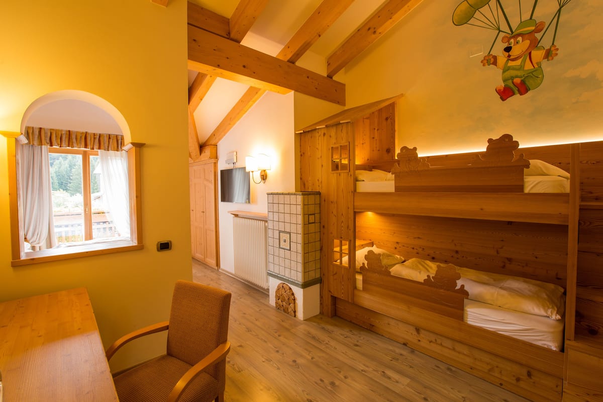 A cozy room with wooden bunk beds, a dining table, and a chair.