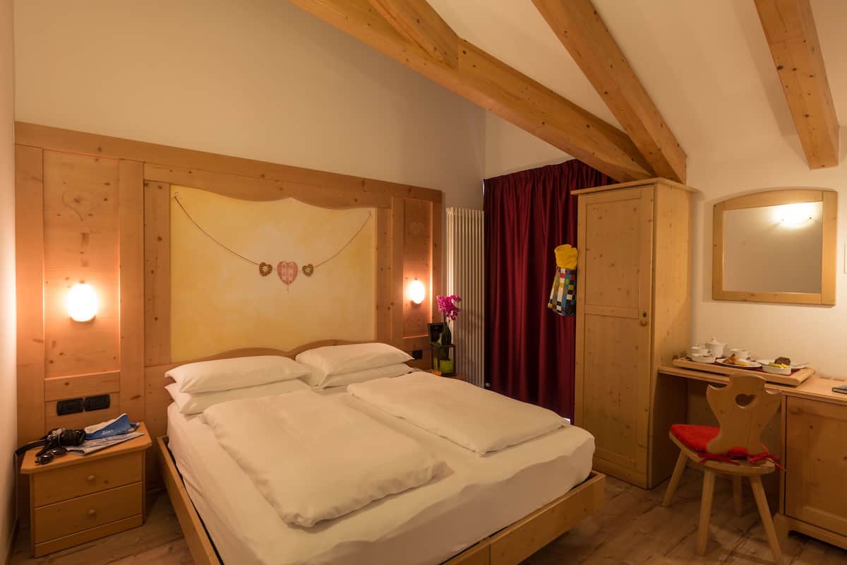 A bedroom with a wooden bed, a nightstand, a desk with a chair, and a wardrobe.