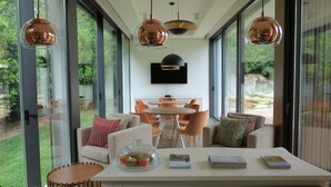 Un interior moderno con comedor, ventanas amplias y televisor en la pared.