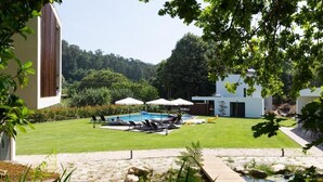 Un patio trasero con piscina, sillas de descanso y sombrillas.