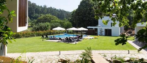 A backyard with a swimming pool, lounge chairs, and umbrellas.