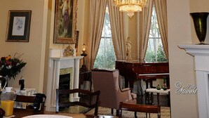 A grand room with a large ornate chandelier, a piano, and a fireplace. - Clermont Bluffs B&B (Natchez)