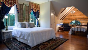 A bedroom with a large bed, a desk, and a chair. There is a window with curtains and a view of greenery outside. - Clermont Bluffs B&B (Natchez)