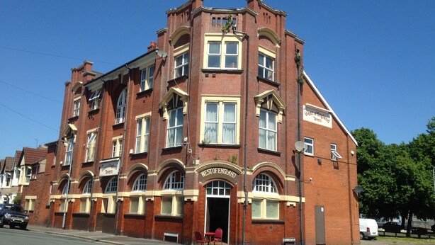 En rød murbygning med et skilt, der siger "West of England Tavern".