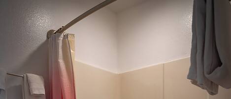 A bathroom with a toilet, a shower curtain, a bathtub, and a towel rack.